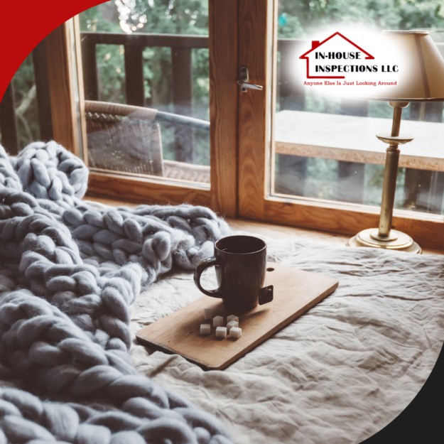 In-House Inspections LLC (13) A cozy bedroom scene with a thick knitted blanket, a cup of coffee on a tray, and a lamp by the window overlooking greenery.