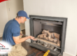 Home inspector examining a gas fireplace with tools and equipment.