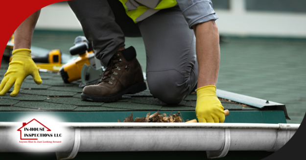 Inspector checking roof edge and clearing debris from a gutter.