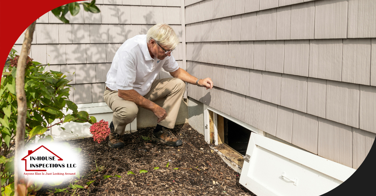 Inspector examining crawl space access outside home.